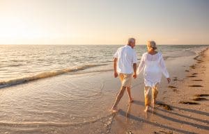 Retired senior couple walking hand in hand on the beach 
