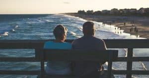 happy retired couple sitting on bench at a florida beach