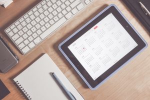 a tablet with calendar, notebook, and a pen