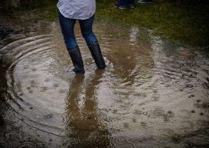 A woman in rubber boots standing in a big puddle